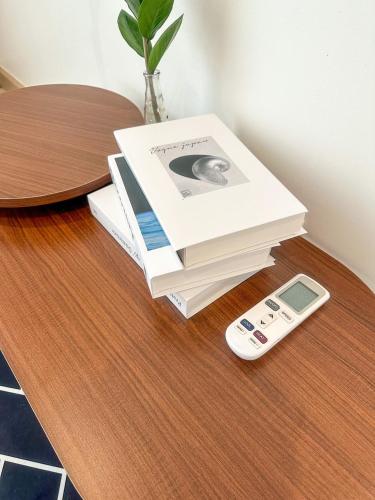 a stack of books on a table next to a remote control at Happy Land Residence in Ban Nam Cham