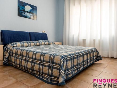 een slaapkamer met een bed met een geruite deken bij Casa Monestir in Sant Feliu de Guixols