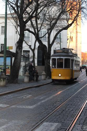a yellow trolley car driving down a city street at Largo da Sé Guest House - HOrigem in Lisbon