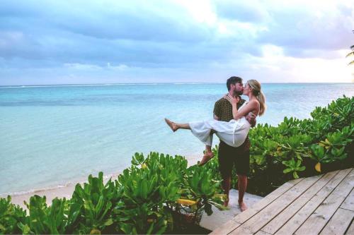 a man and woman standing on the beach with the ocean at Sea Change Villas in Rarotonga