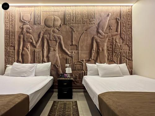 a room with two beds and a wall with a mural at Giza Pyramids View Inn in Cairo