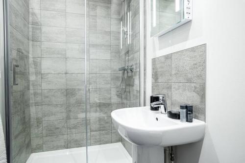 a white bathroom with a sink and a shower at Apartments in Peterborough City Centre - Bayard Plaza in Peterborough
