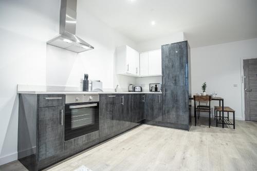 a kitchen with wooden cabinets and a table in it at Apartments in Peterborough City Centre - Bayard Plaza in Peterborough