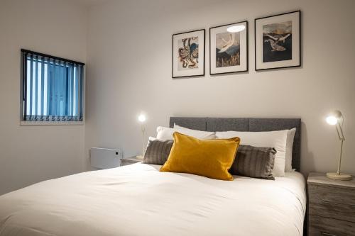 a bedroom with a large white bed with yellow pillows at Apartments in Peterborough City Centre - Bayard Plaza in Peterborough