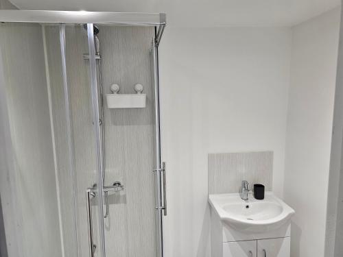a white bathroom with a shower and a sink at Skyline Remarkable 2-Bed Apartment in Swansea in Swansea