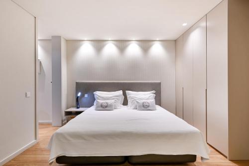 um quarto com uma grande cama branca e 2 almofadas em Sé Apartamentos - Sé INN Studios em Braga