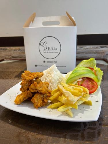 a plate of food withfried chicken and chips and a box at Jultom Inn Hotel & Suites in Trujillo