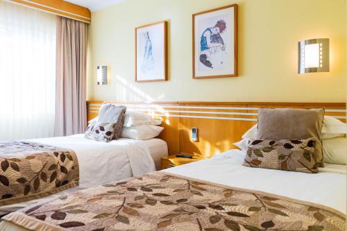 a hotel room with two beds and a window at Hotel Restaurante Ankara in Viña del Mar