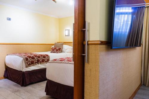 a room with two beds and a flat screen tv at Hotel Restaurante Ankara in Viña del Mar