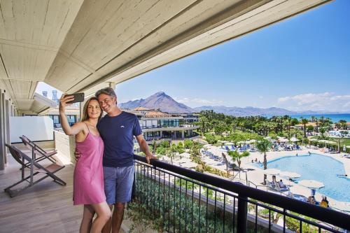 un hombre y una mujer de pie en el balcón de un complejo en Grand Palladium Sicilia Resort & Spa en Campofelice di Roccella