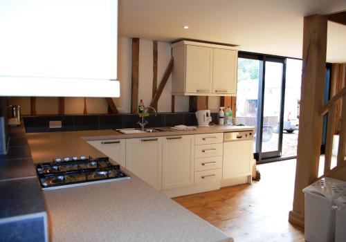a kitchen with white cabinets and a counter top at Holiday Home Virginia Barn in East Harling