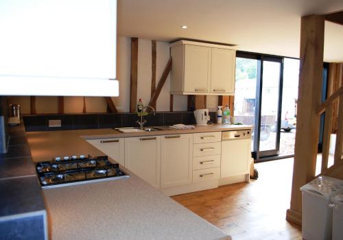 una cucina con armadi bianchi e piano di lavoro di Holiday Home Virginia Barn a East Harling