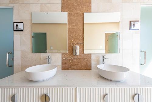 two sinks in a bathroom with two mirrors at Brickell Apart Hotel in Santo Domingo