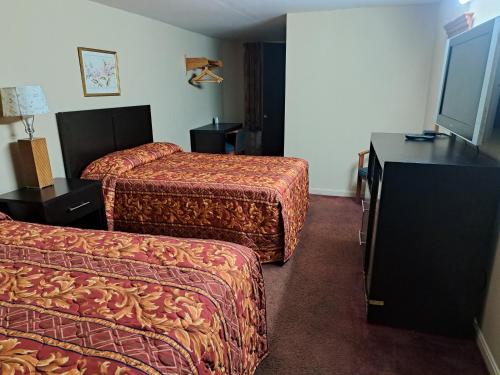 a hotel room with two beds and a television at Pennswoods Inn in Manheim