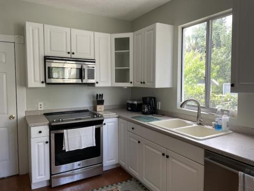 a kitchen with white cabinets and a sink and a stove at The Painted Lady, a spacious renovated 4BR Victorian in St. Augustine