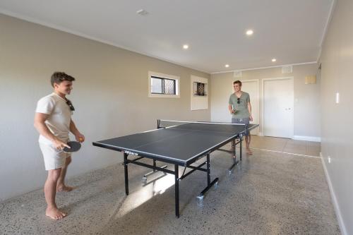 two men standing in a room with a ping pong table at Sea Change Villas in Rarotonga