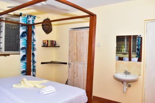 ein Schlafzimmer mit einem Bett und einem Waschbecken in der Unterkunft Double room in a villa in Diani Beach