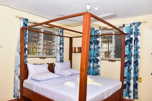 a bedroom with a four poster bed and two windows at Double room in a villa in Diani Beach