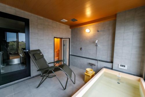 a bathroom with a chair and a bath tub at Ise-Shima Ohtaya Healing Stay in Toba