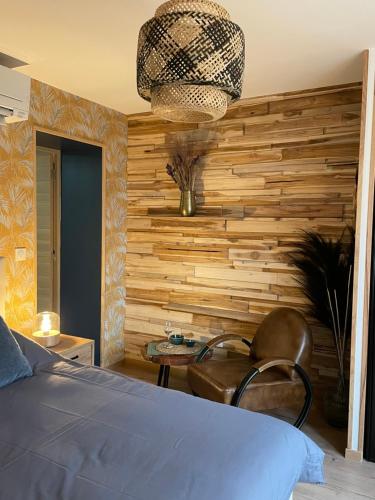 - une chambre dotée d'un mur en bois avec un lit et une chaise dans l'établissement Appart équipé 2 personnes, à Saint-Amand-les-Eaux