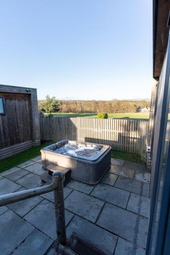 a hot tub sitting on a patio next to a fence at Ribblesdale Park in Gisburn