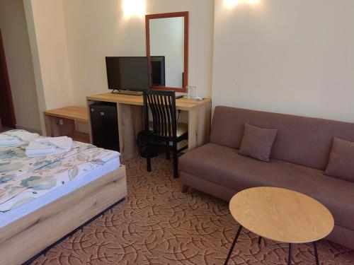 a living room with a couch and a desk with a television at Family Hotel Diana in Tsarevo