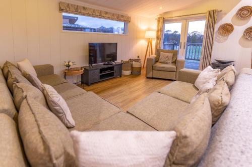 a living room with a large couch and a tv at Ribblesdale Park in Gisburn