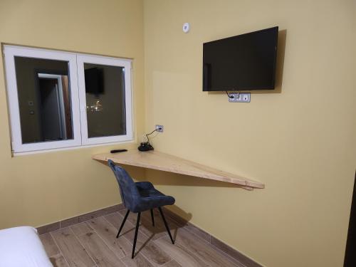 a room with a desk with a tv and a chair at Chambres Jura Sud in Charchilla