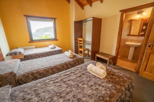 um quarto de hotel com duas camas e um lavatório em Hosteria El Paraiso em El Chaltén