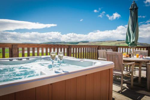 a hot tub on a deck with a table and chairs at Barn Lodge with Hot Tub in Cupar