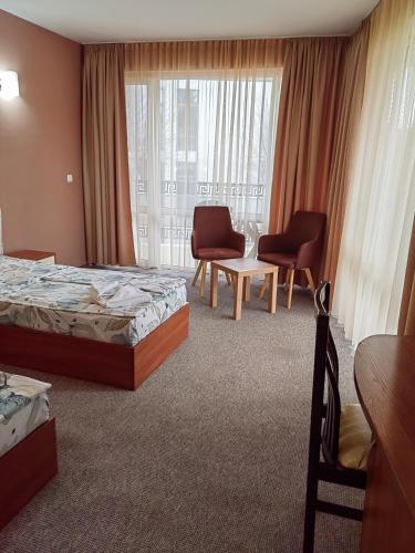 a hotel room with two beds and chairs and a window at Family Hotel Diana in Tsarevo