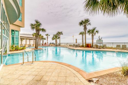 une piscine bordée de palmiers et un bâtiment dans l'établissement Aqua 1604, à Panama City Beach