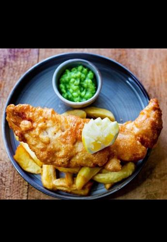 une assiette bleue avec du poisson, des frites et une sauce dans l'établissement The Okeover Arms, à Ashbourne