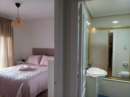 een slaapkamer met een bed, een wastafel en een spiegel bij Apartamento el Ermitaño in Chipiona