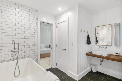Baño blanco con bañera y lavamanos en Ruschmeyers Hotel, en Montauk
