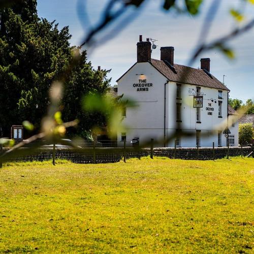 an old white building in a field of grass at The Okeover Arms in Ashbourne