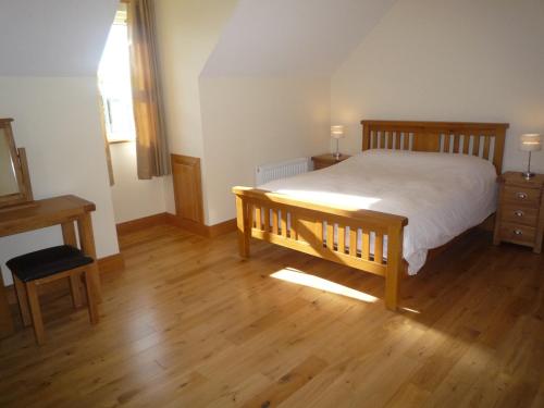 a bedroom with a bed and a wooden floor at Derryleigh House 