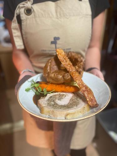 a person holding a plate of food with meat and vegetables at The Crossroads Inn in Halifax