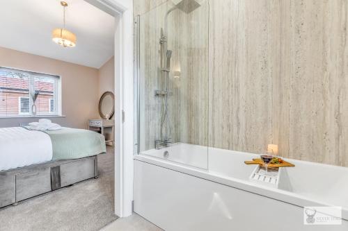 ein Bad mit einer Badewanne, einem Bett und einer Dusche in der Unterkunft Silver Stag Properties, Luxury Cabin w SK Bed 