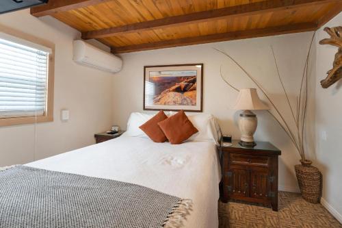 a bedroom with a white bed and a lamp and a window at Stone Lizard Lodge in Blanding