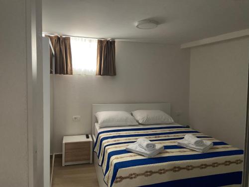 a bedroom with a bed with a blue and white striped blanket at Tisno Resort in Tisno
