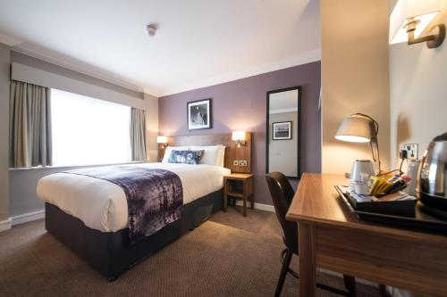 a hotel room with a bed and a desk with a computer at The Swan by Innkeeper's Collection in Coleshill