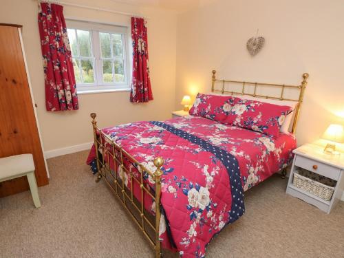 a bedroom with a red bed and a window at Holly Cottage in Ventnor