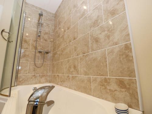uma casa de banho com um chuveiro e uma banheira com um lavatório em Holly Cottage em Ventnor