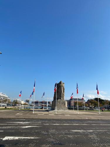 a monument with flags in front of a building at Oscar Hôtel Le Havre Centre in Le Havre