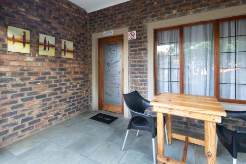 a room with a wooden table and chairs and a brick wall at Stevenski's Guesthouse in Lephalale