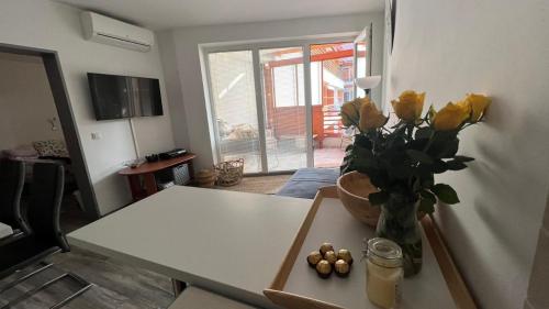 un soggiorno con tavolo e vaso di rose gialle di Apartma Rakita a Moravske Toplice