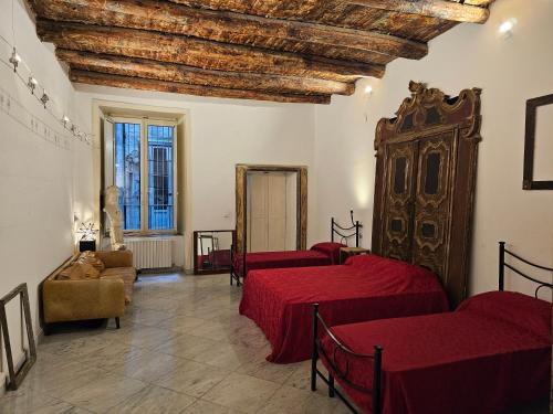 Cette chambre comprend 3 lits avec des draps rouges. dans l'établissement The Spanish Palace Rooms, Suites Apartments & Terraces, à Naples