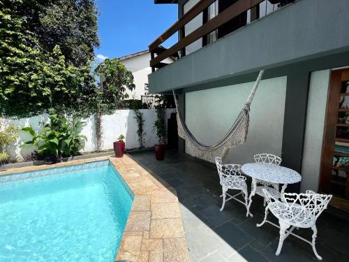 un patio con mesa y sillas junto a una piscina en A Casa que Hospeda, en São Paulo