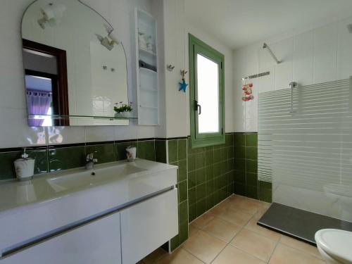 y baño con lavabo, espejo y ducha. en Estupendo Apartamento Gaudia, en Caleta de Fuste